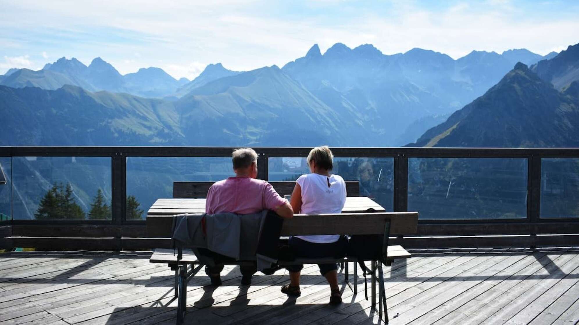 Ein Mann und eine Frau an einem Tisch vor Bergpanorama