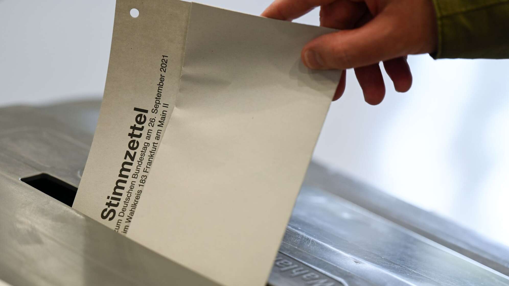 Stimmzettel wird in eine Wahlurne gesteckt